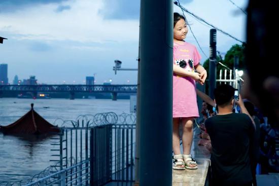 7月13日，湖北武汉市，市民在即将被淹没的武昌黄花矶凉亭前拍照。图/人民视觉